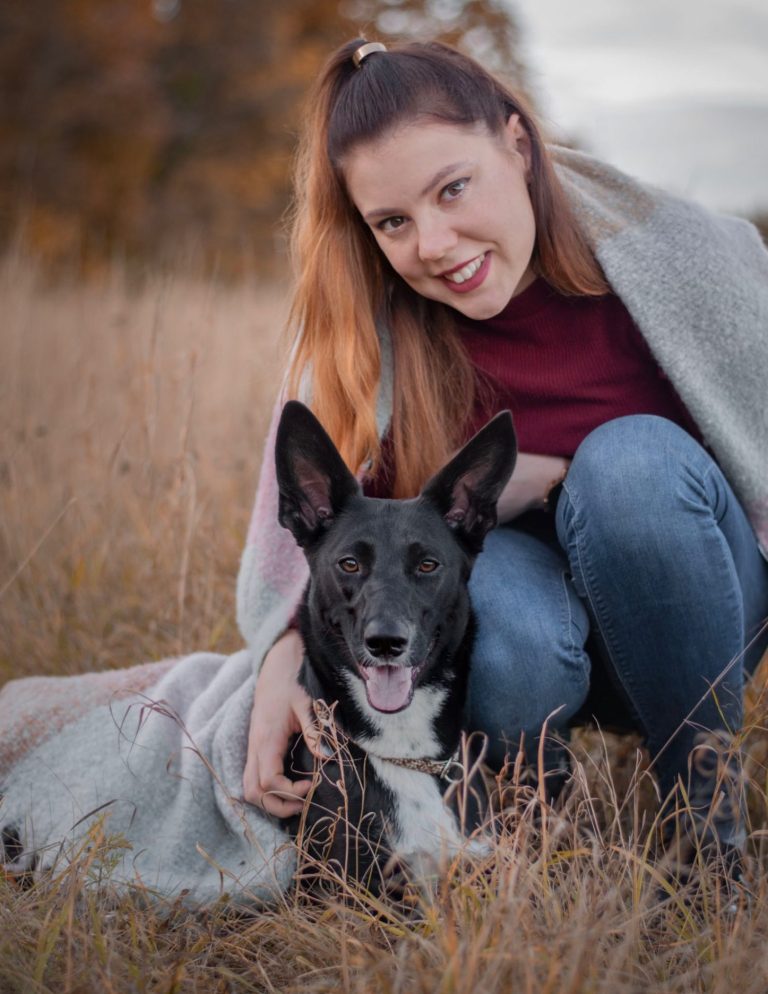 Ein herbstliches Portrait von einer Frau mit ihrem Hund in einem Feld